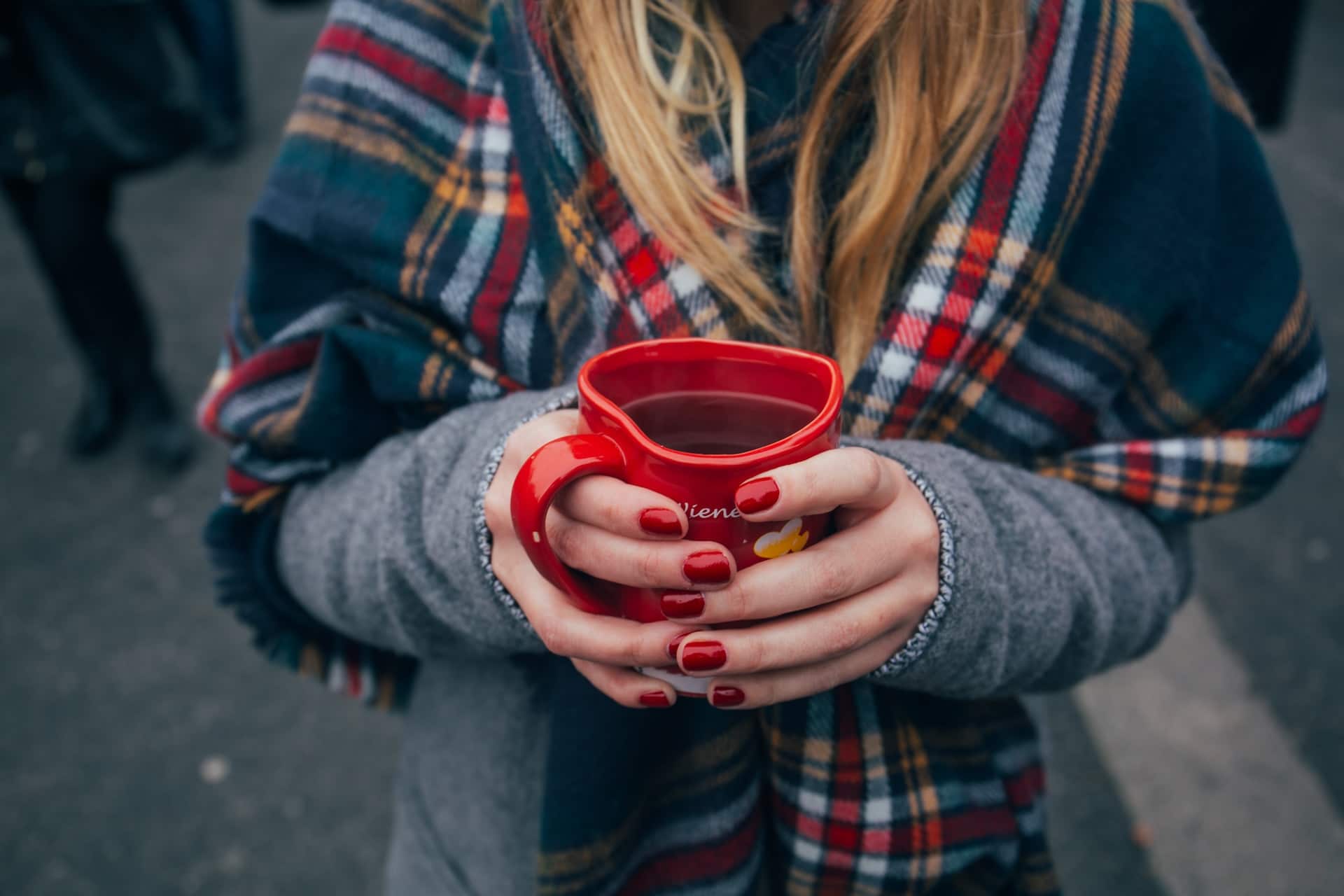 Woman with red nail polish holding a mug
