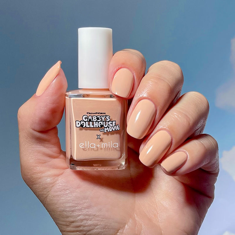 Gabby's Dollhouse Baby Box Peach nail polish manicure on a medium skin tone, holding the bottle