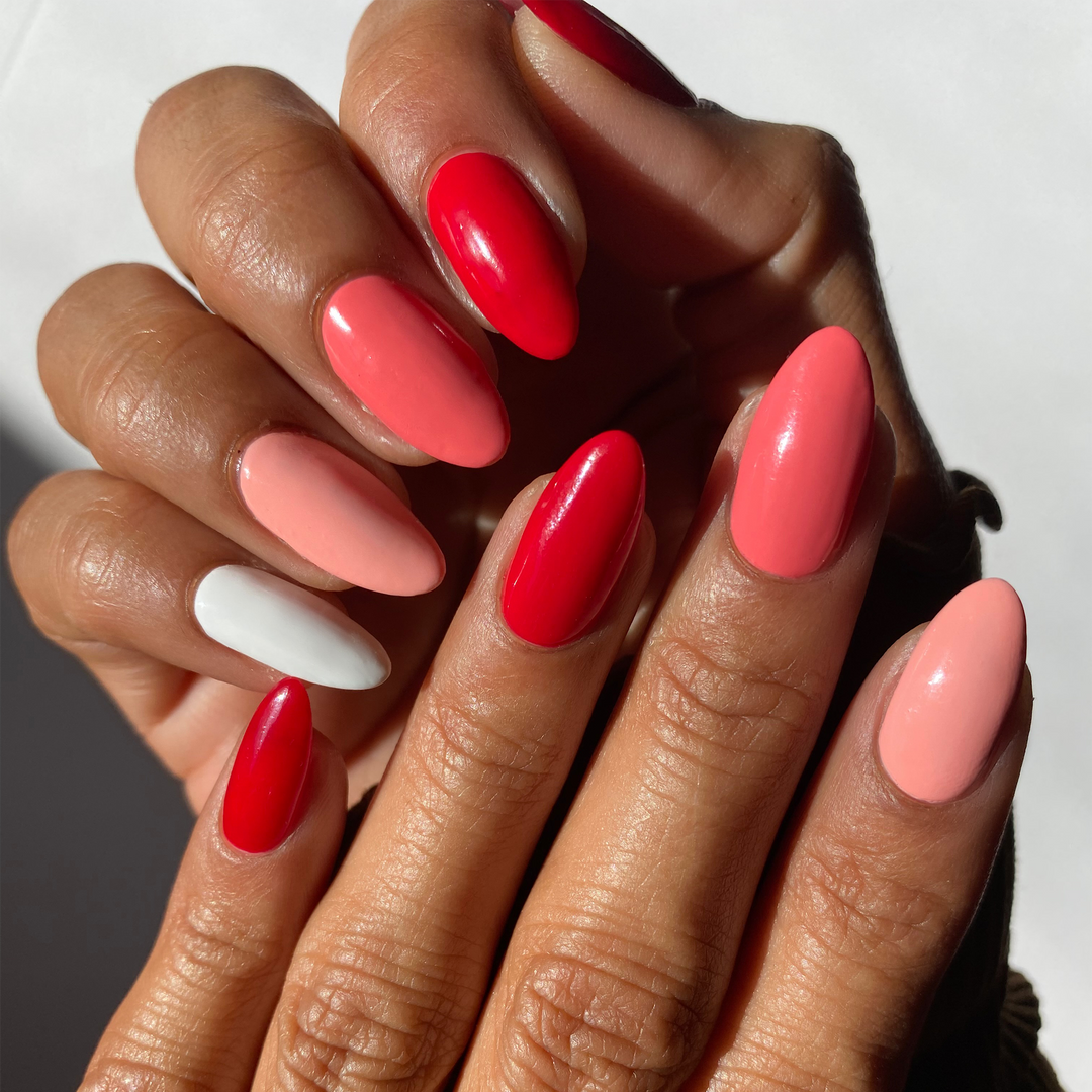 Candy Cane Dreams red, coral and white mix-and-match manicure on a medium skin tone