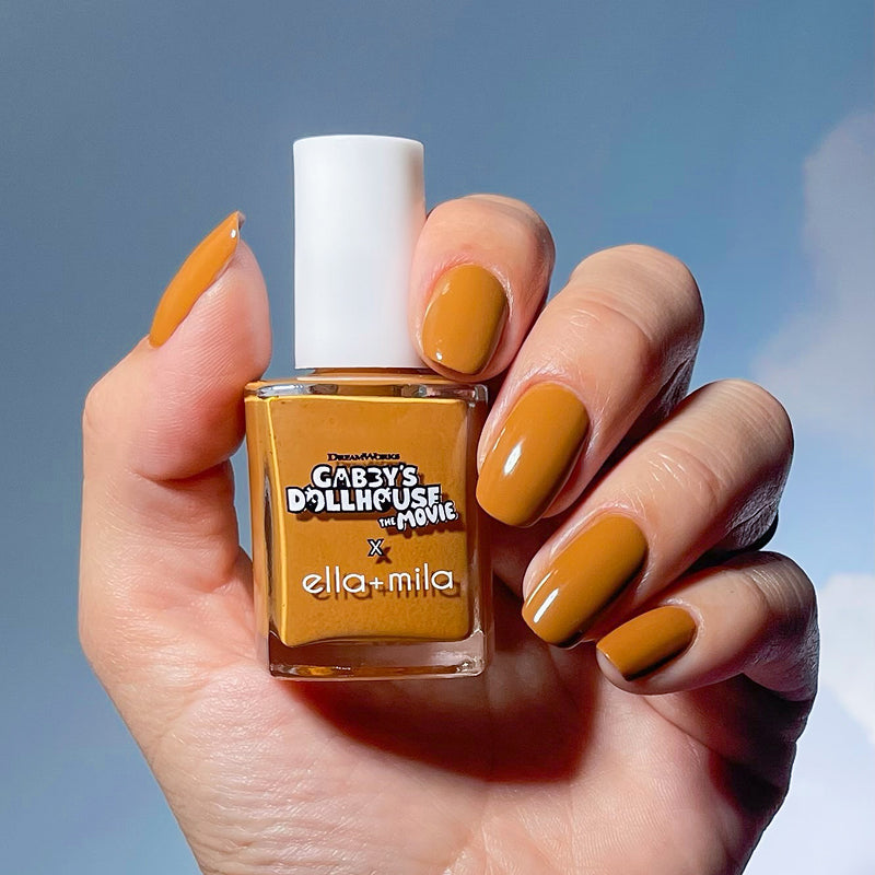 Gabby's Dollhouse Chumsley's Charm caramel nail polish manicure on a medium skin tone, holding the bottle