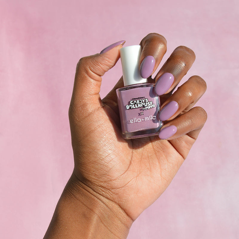 Gabby's Dollhouse DJ Catnip Party Time lilac nail polish on a deep skin tone, hand holding the bottle