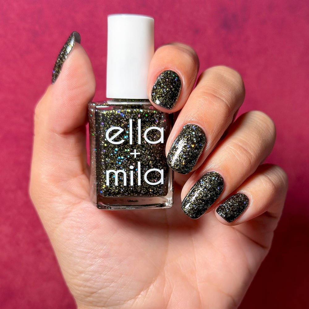 Descendants Hatter's Revenge black glitter nail polish on a light skin tone, hand holding the bottle