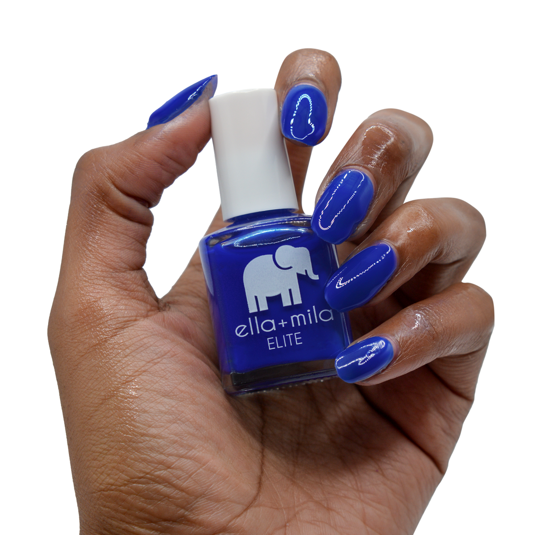 Bags Are Packed royal blue nail polish on a deep skin tone, hand holding the bottle