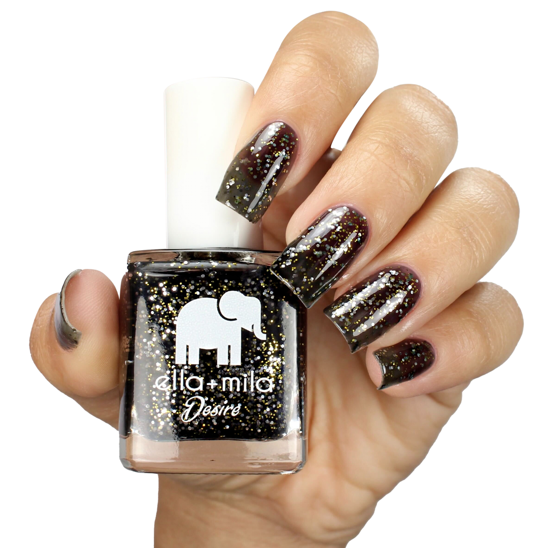 Black Tie Affair black tinted glitter nail polish on a medium skin tone, holding the bottle