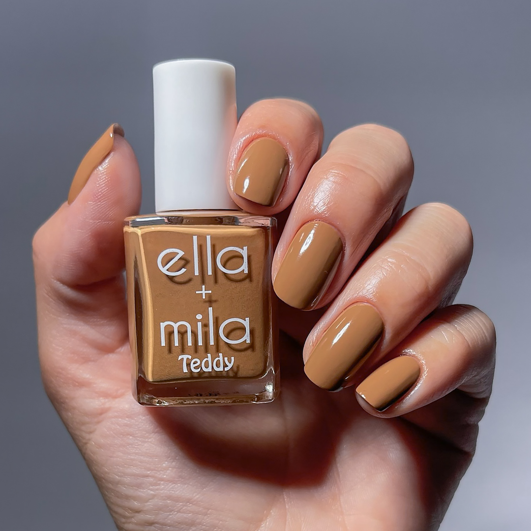 Caramel Cub medium chestnut brown nail polish manicure on a light skin tone, holding the bottle