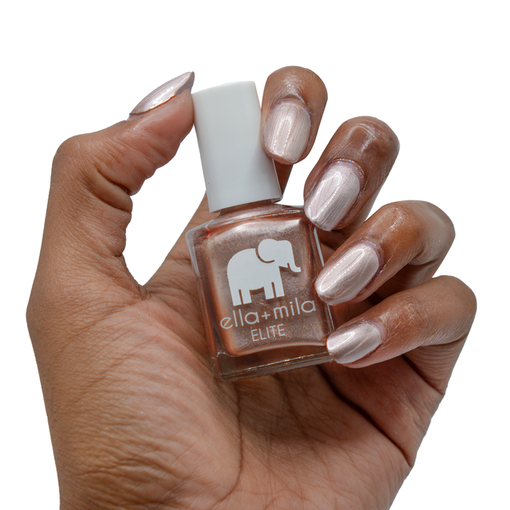 Champagne Pop metallic rose gold nail polish on a deep skin tone, hand holding the bottle