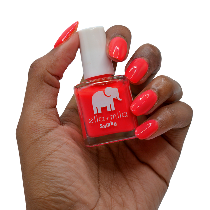 Coral Crush orange coral nail polish on a deep skin tone, hand holding the bottle