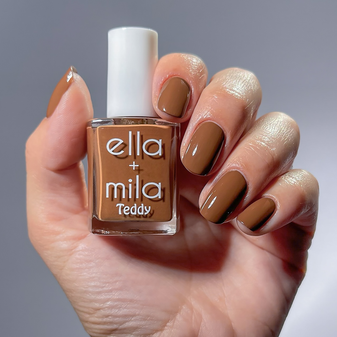 Cuddle Up cocoa brown nail polish manicure on a light skin tone, holding the bottle