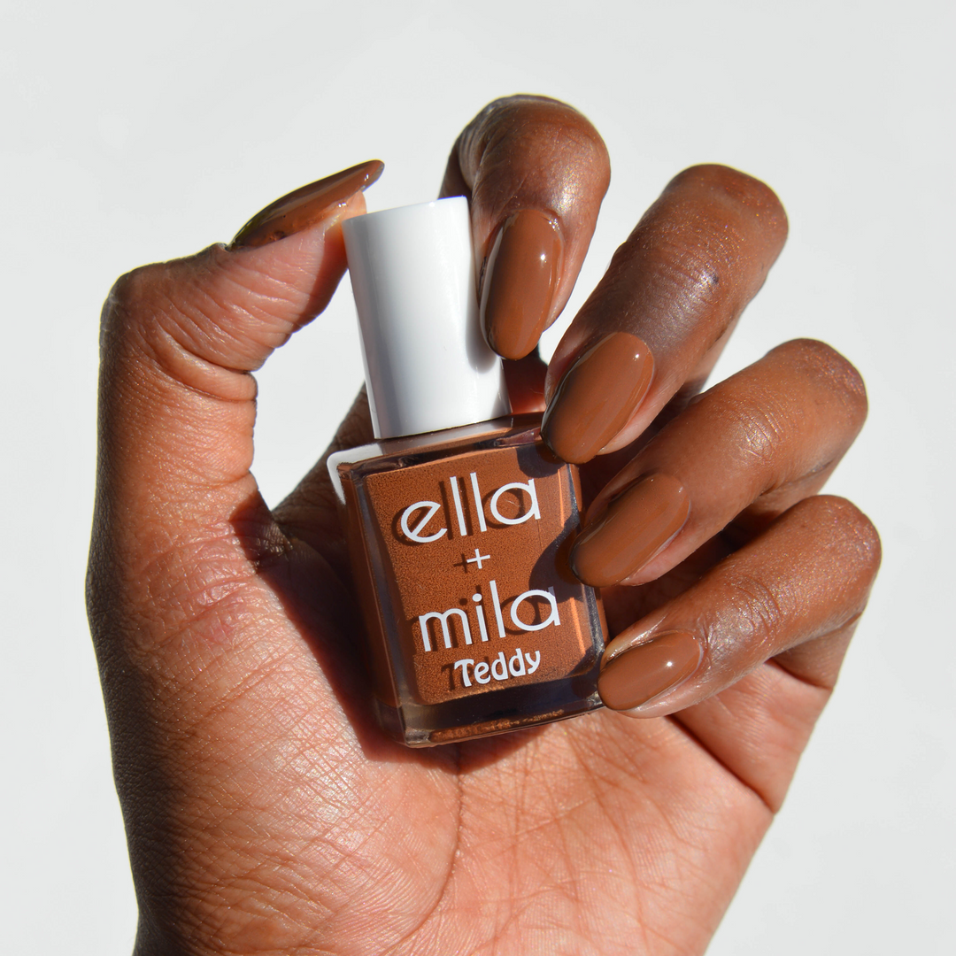 Cuddle Up true cocoa brown nail polish on a deep skin tone, hand holding the bottle