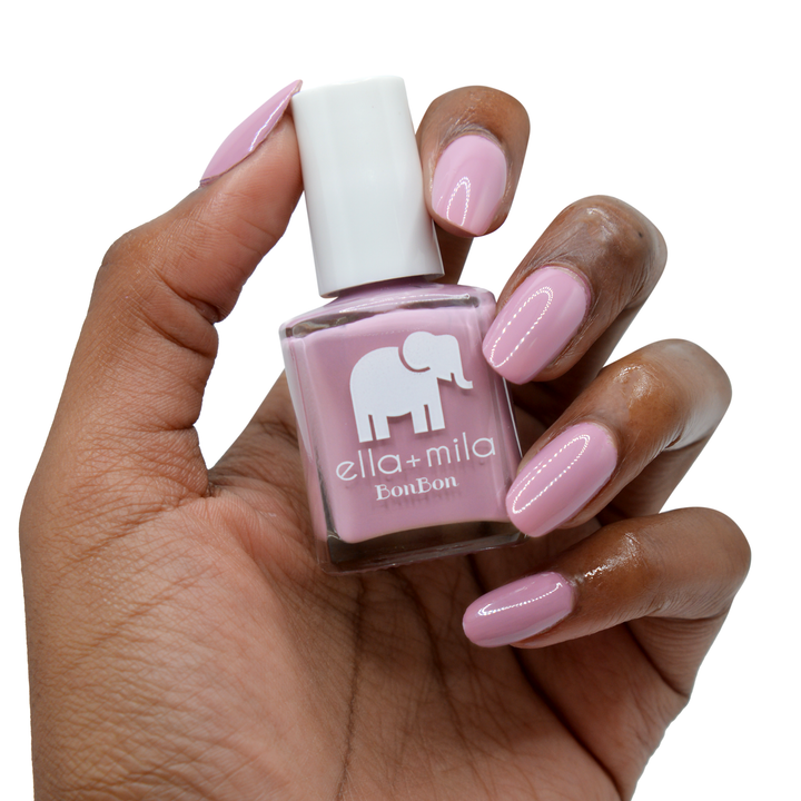 Dulce Amor dusty rose nail polish on a deep skin tone, hand holding the bottle
