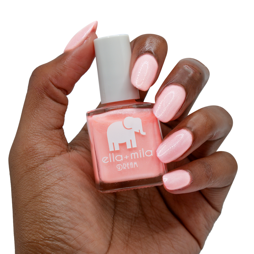 Glisten to Me shimmery pale pink nail polish on a deep skin tone, hand holding the bottle