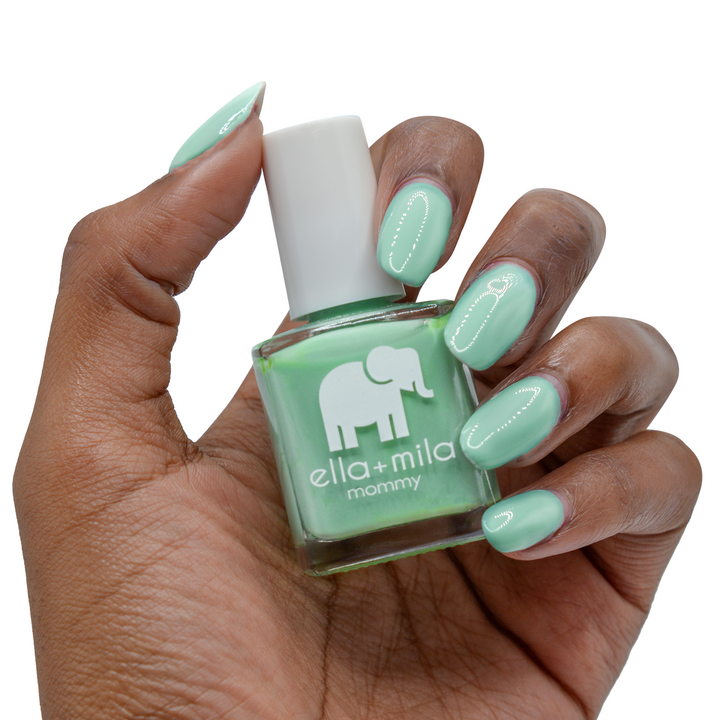I Mint It mint green nail polish on a deep skin tone, hand holding the bottle
