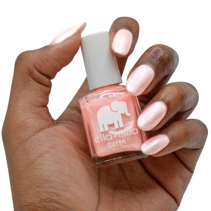 My Fantasy pearly pink nail polish on a deep skin tone, hand holding the bottle