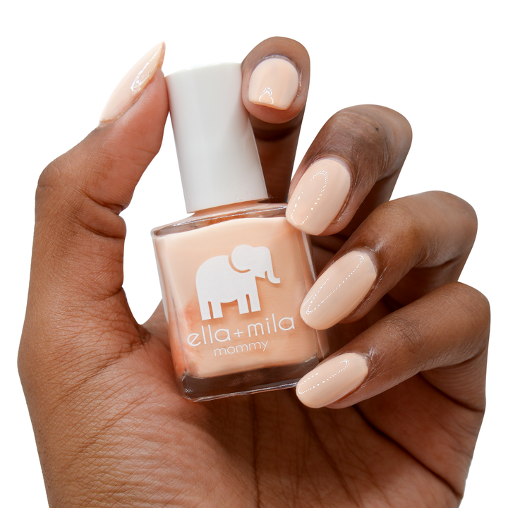 Nude Attitude peachy nude nail polish on a deep skin tone, hand holding the bottle