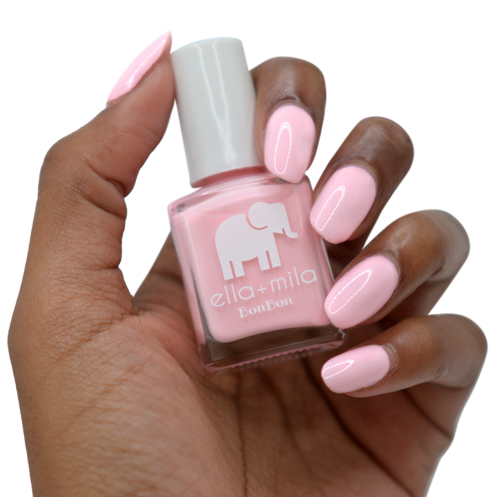 Pink Drink light pink nail polish on a deep skin tone, hand holding the bottle