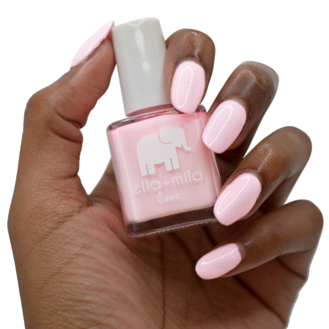 Pink Me Up baby pink nail polish on a deep skin tone, hand holding the bottle