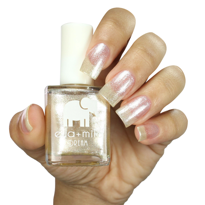 Pixie Dust sheer shimmer nail polish on a medium skin tone, hand holding the bottle