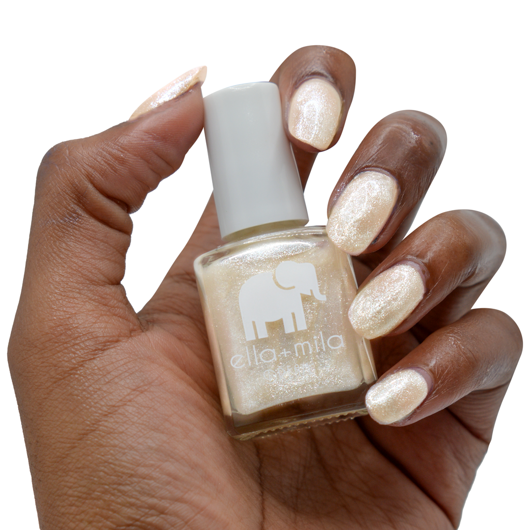 Pixie Dust sheer frosted shimmer nail polish on a deep skin tone, hand holding the bottle