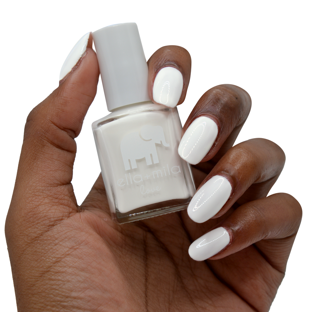 Pure Love white nail polish on a deep skin tone, hand holding the bottle