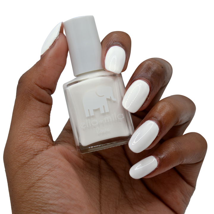 Pure Love white nail polish on a deep skin tone, hand holding the bottle