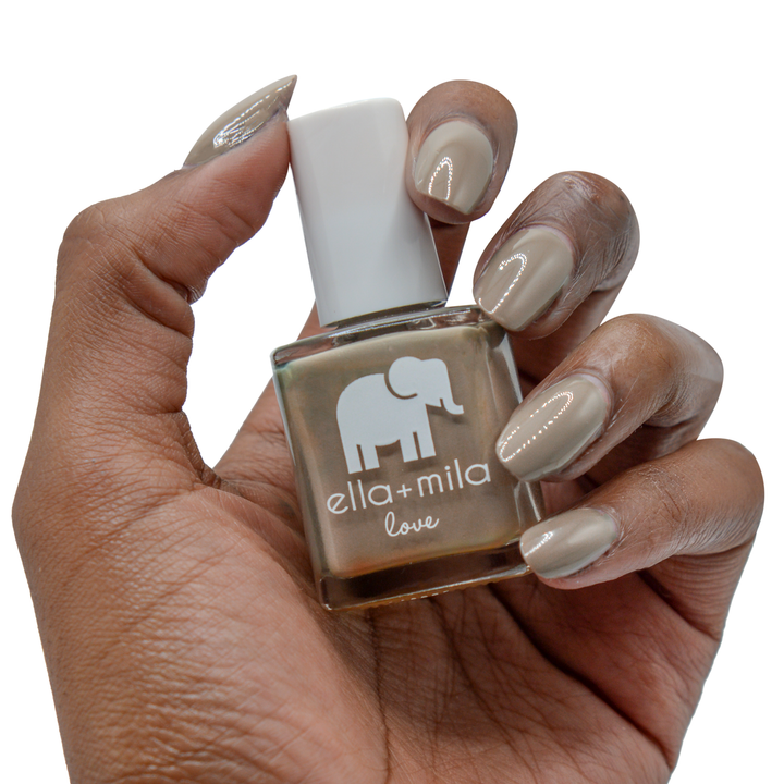 Sandstorm grey brown nail polish on a deep skin tone, hand holding the bottle