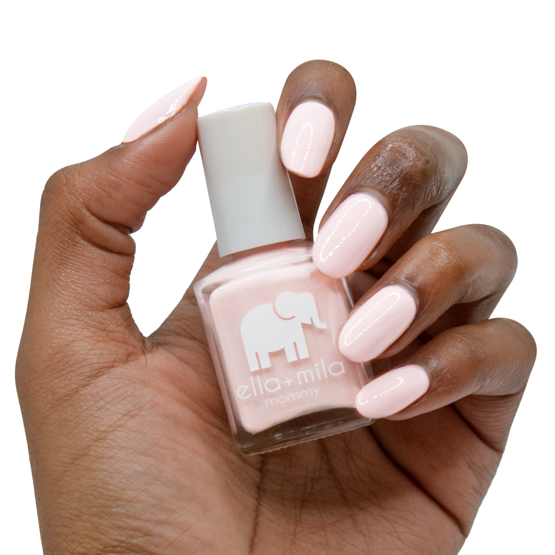 So in Love pastel pink nail polish on a deep skin tone, hand holding the bottle