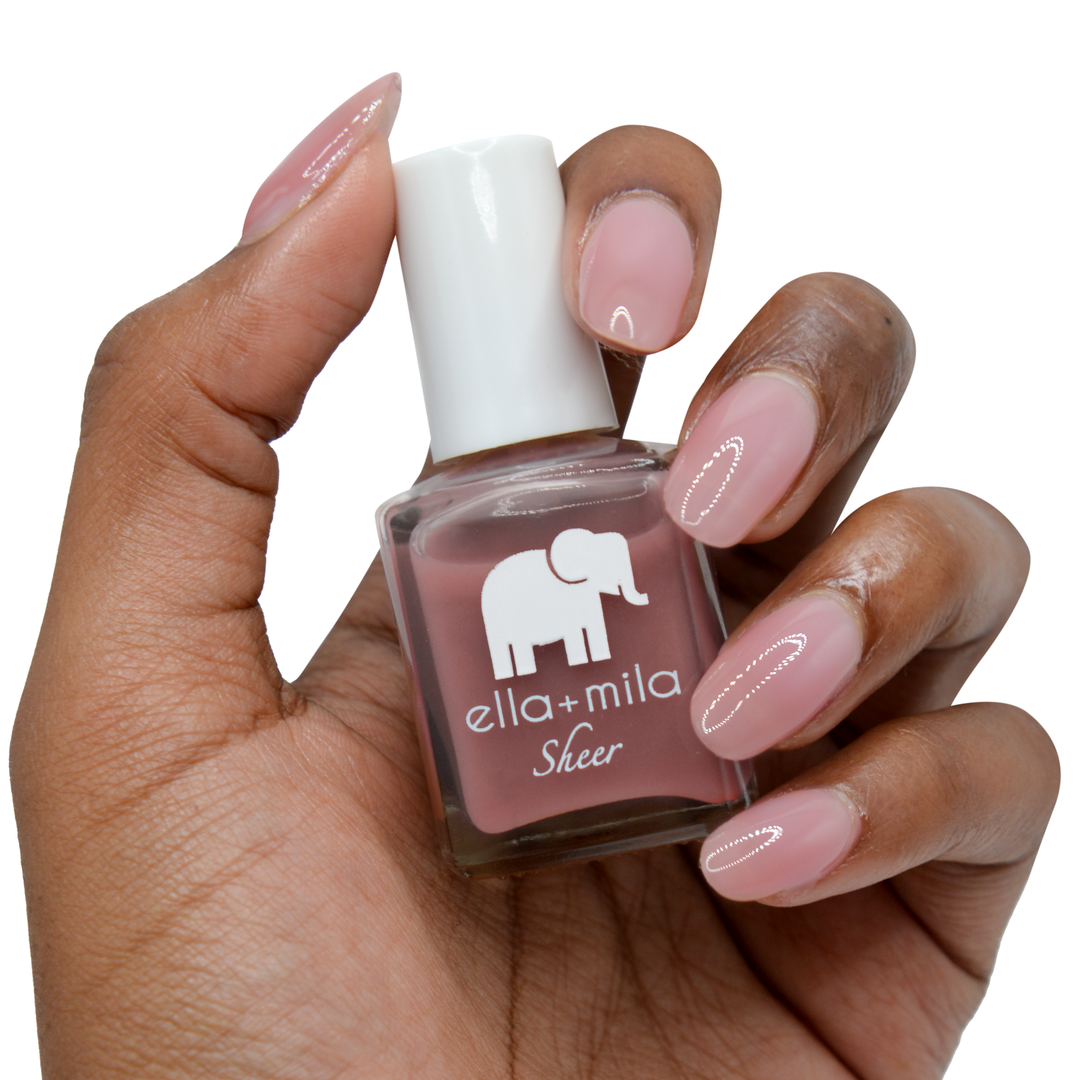 Strong sheer mauve tint nail polish on a deep skin tone, hand holding the bottle