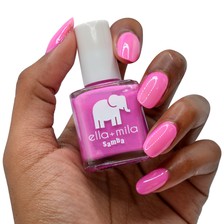 Sun Has Set hot pink nail polish on a deep skin tone, hand holding the bottle