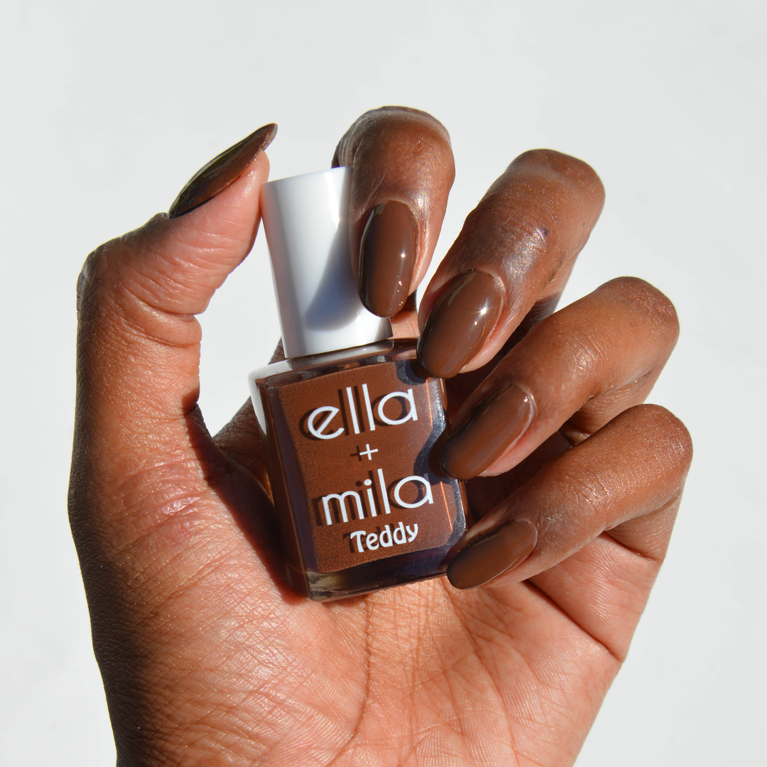 The Snuggle is Real cocoa brown nail polish on a deep skin tone, hand holding the bottle