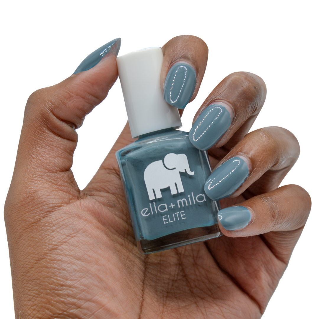 Yacht Club grey blue-green nail polish on a deep skin tone, hand holding the bottle
