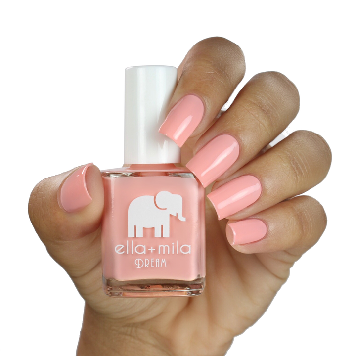 Bubble Trouble peachy pink nail polish on a medium skin tone, hand holding the bottle