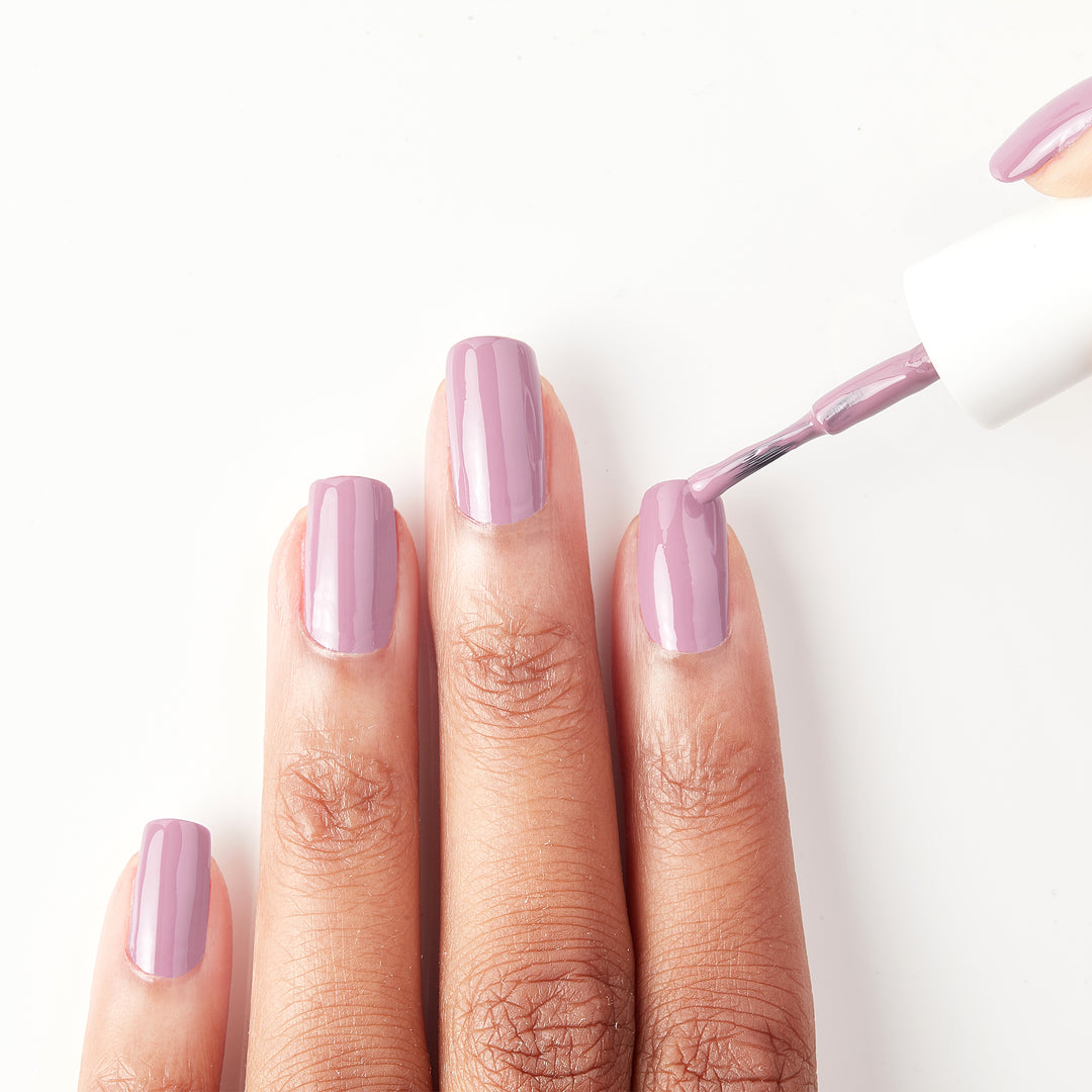 Applying Dulce Amor dusty rose nail polish to the nails