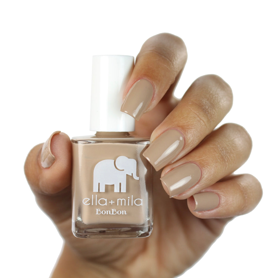 Mocha Dreams neutral brown nail polish on a medium skin tone, hand holding the bottle