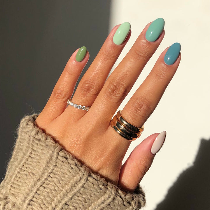 Paradise Isle green and pink colorblock nail art on a medium skin tone with rings