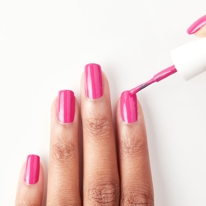 Applying Sun Has Set hot pink nail polish to the nails