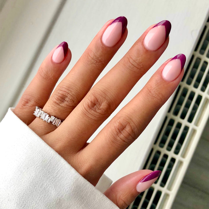 Take Off berry pink French tip nail art with rings on a light skin tone