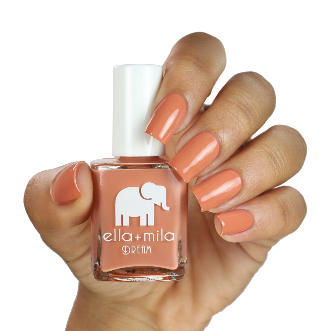 A La Nude soft burnt-orange brown nail polish on a medium skin tone, hand holding the bottle