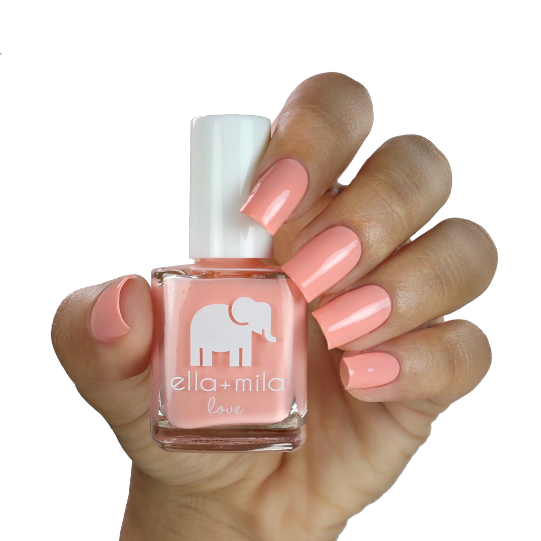 A Proposal peach coral nail polish on a medium skin tone, hand holding the bottle