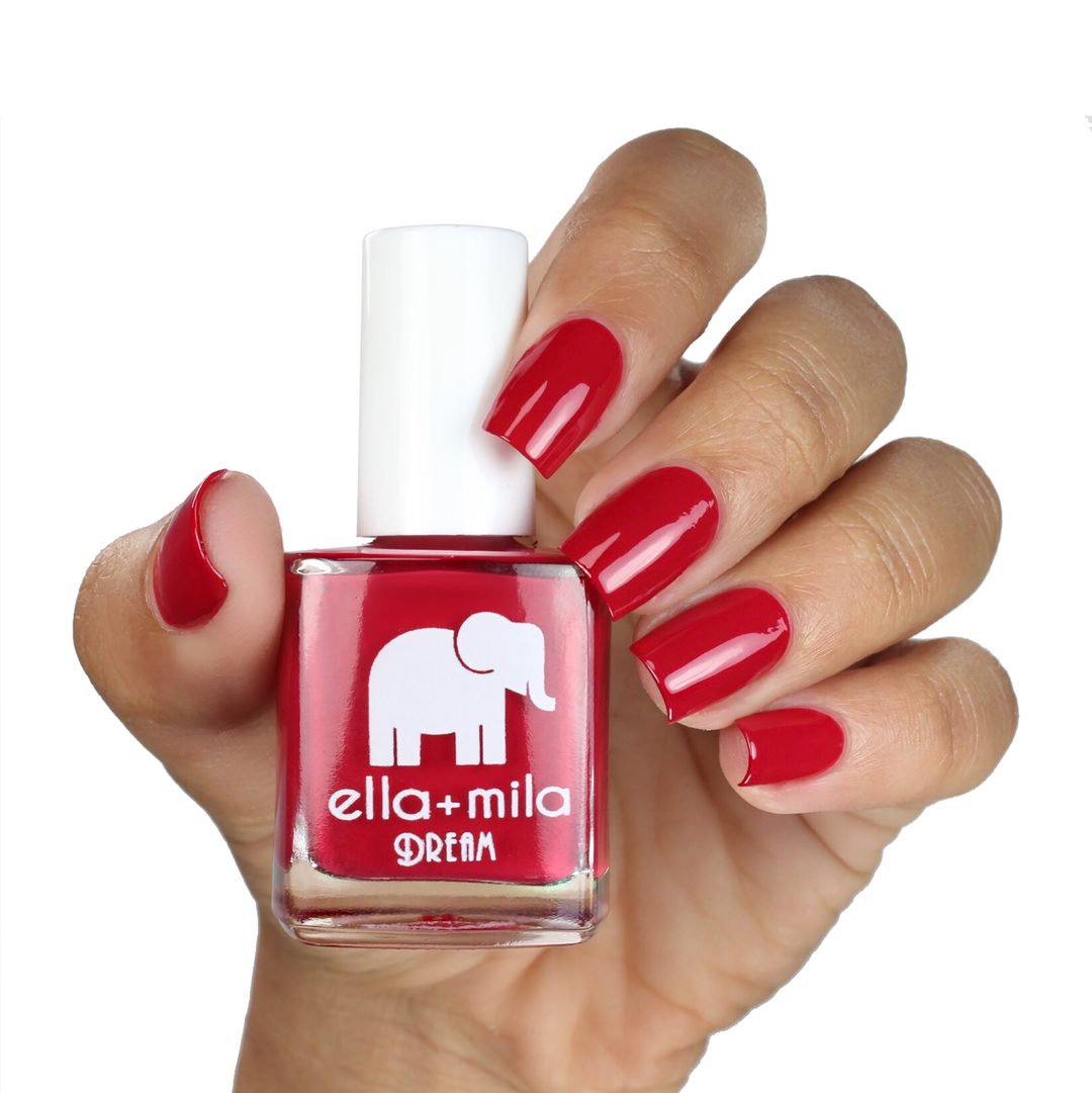 Bad Obsession raspberry red nail polish on a medium skin tone, hand holding the bottle