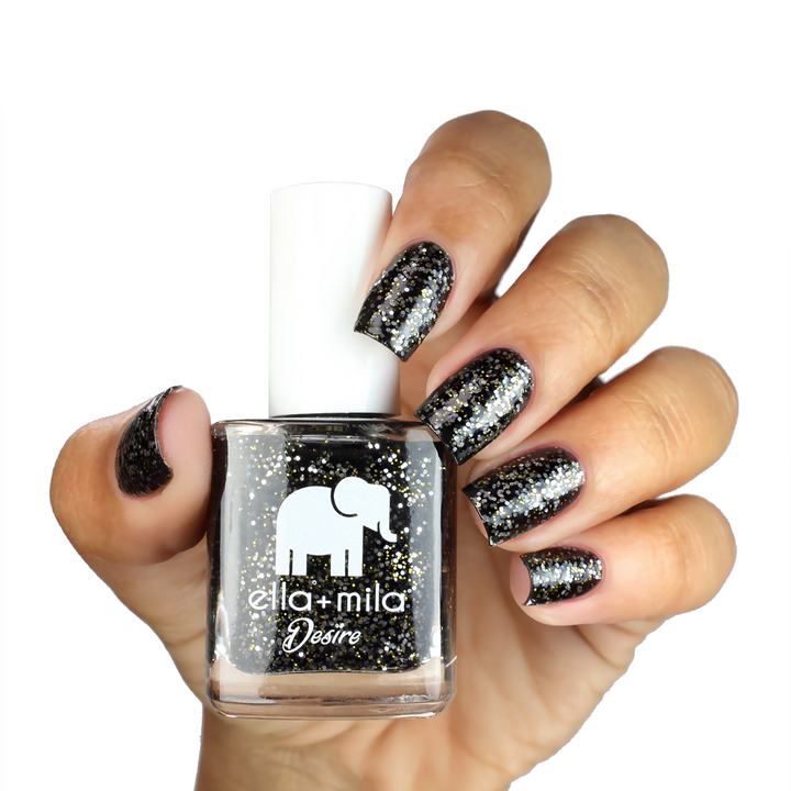 Black Tie Affair black glitter nail polish on a medium-deep skin tone, hand holding the bottle