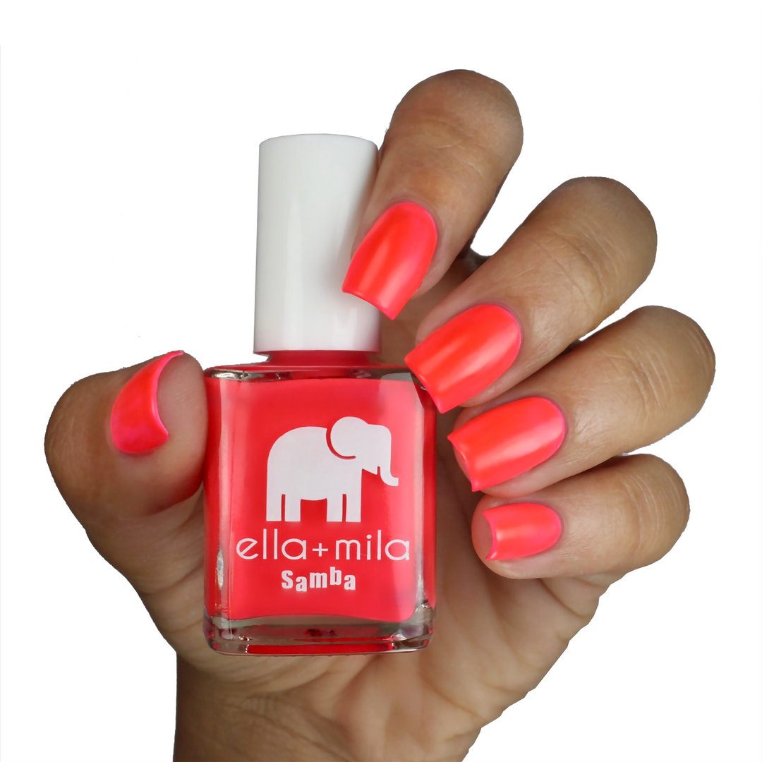 Coral Crush orange coral pink nail polish on a medium skin tone, hand holding the bottle