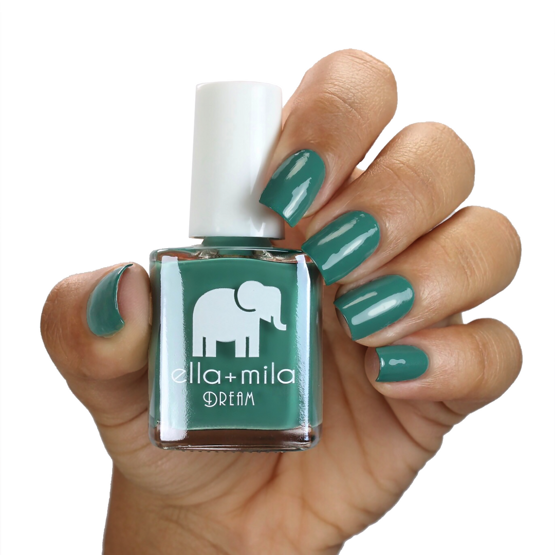 Daydreamer green nail polish on a medium skin tone, hand holding the bottle