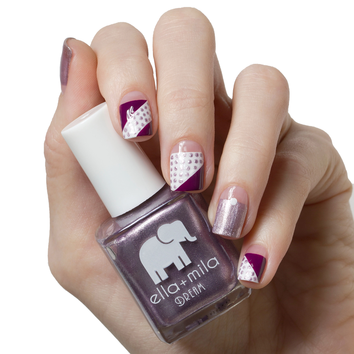 Dolled Up metallic purple nail polish with plum and lace accent nails, holding the bottle