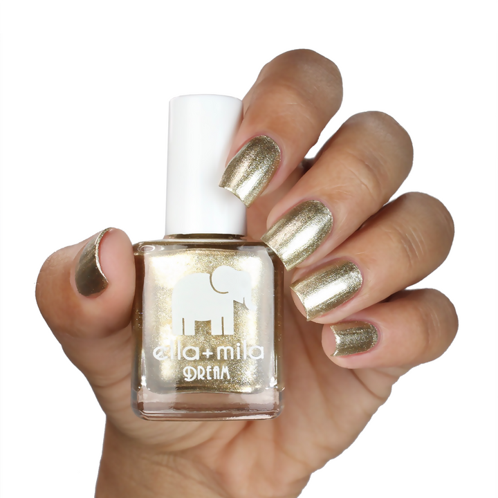 Gilded metallic gold nail polish on a medium skin tone, hand holding the bottle