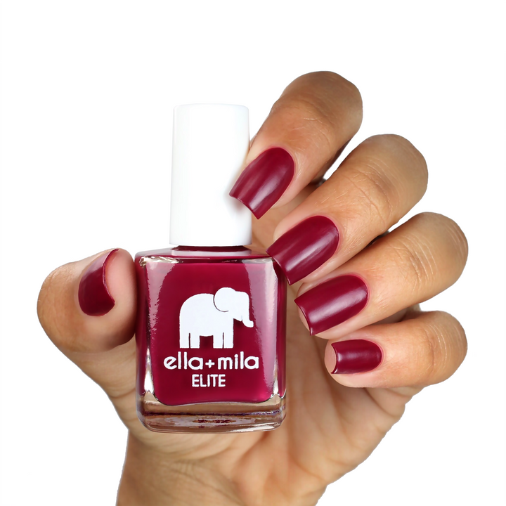 In Line for Wine merlot red nail polish on a medium skin tone, hand holding the bottle