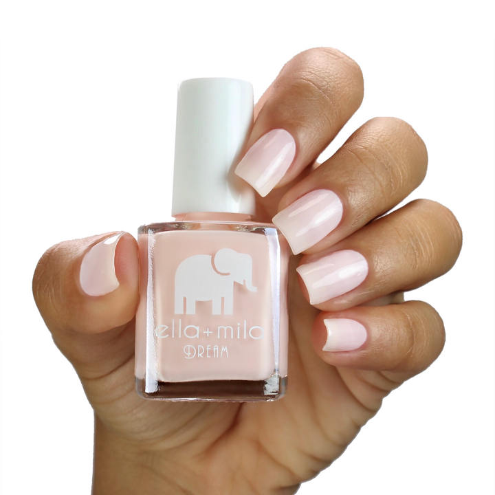 La La Land nude pink nail polish on a medium skin tone, hand holding the bottle