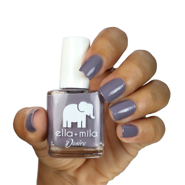 Mauve Over muted grey-purple nail polish on a medium skin tone, hand holding the bottle