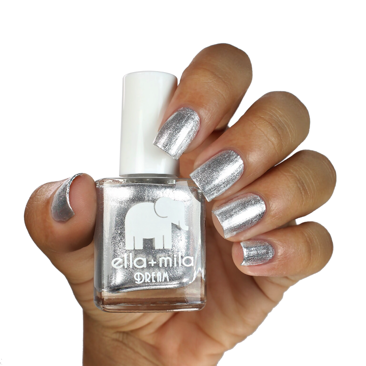 Mirror Mirror silver chrome nail polish on a medium-deep skin tone, hand holding the bottle