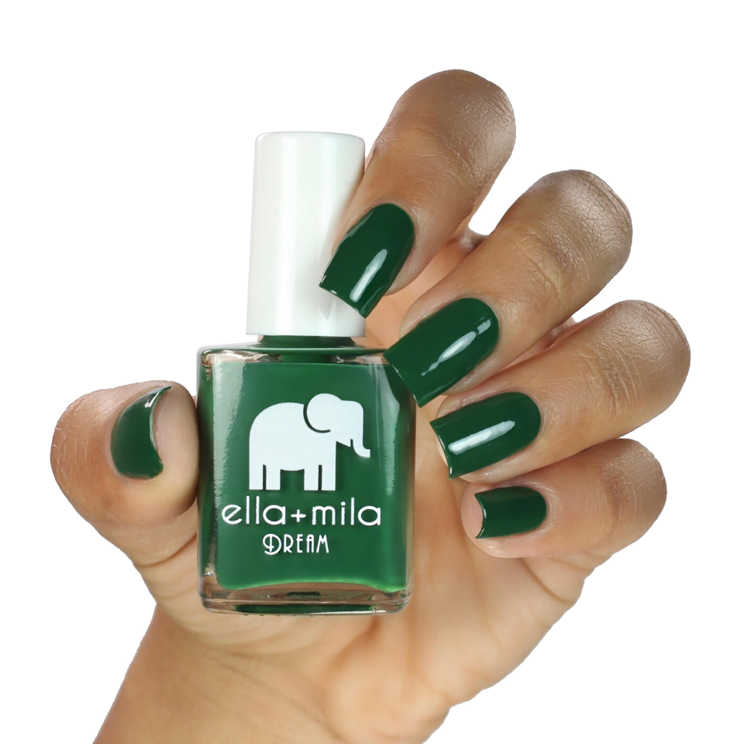 Mistletoe Magic dark green nail polish on a medium skin tone, hand holding the bottle