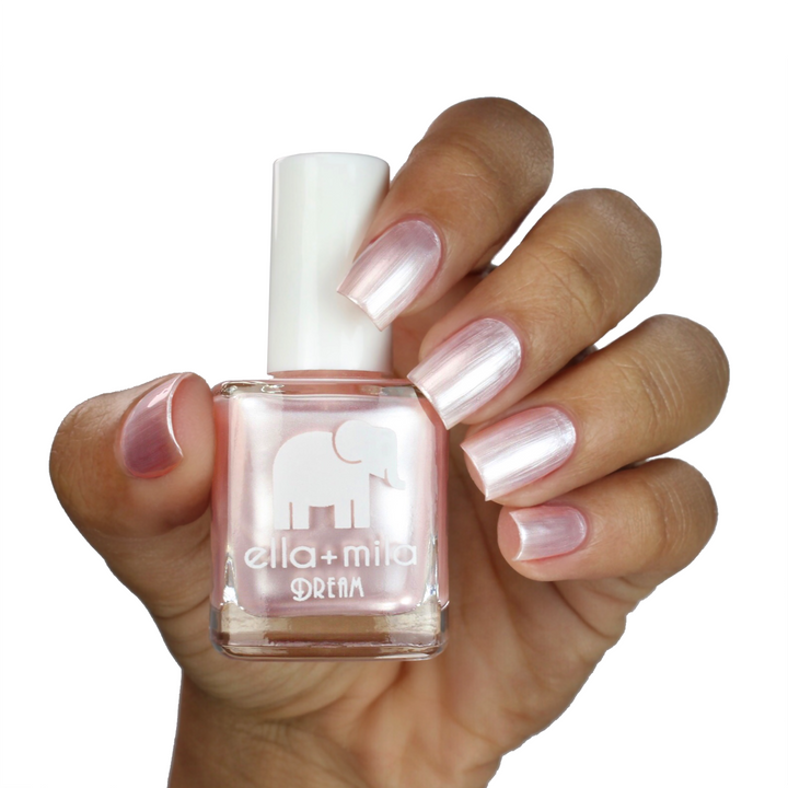 My Fantasy pearl pink nail polish on a medium skin tone, hand holding the bottle